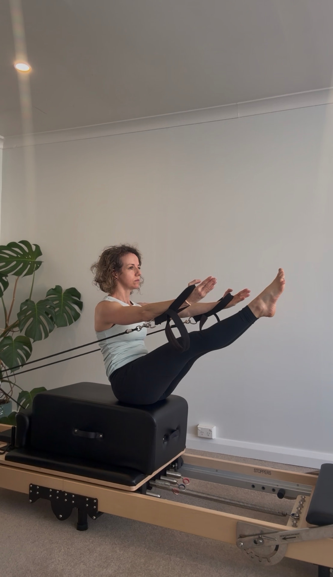 Client holding a teaser on the reformer box with the straps in the West Hobart studio